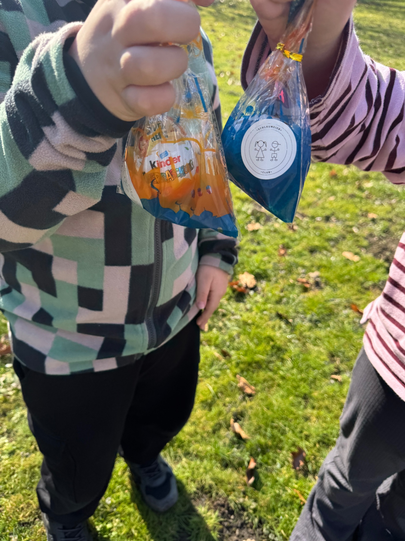 Zwei Kinder zeigen stolz ihre gefundenen Tüten in die Kamera