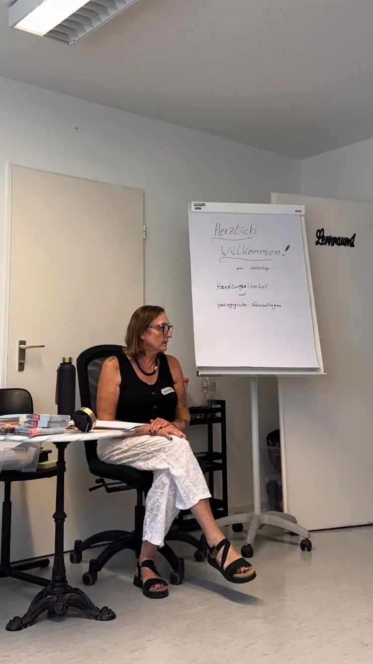 Pädagogische Leitung des Schlaumeierclubs vor dem Flipchart mit der Begrüßung zum Workshop Handlungssicherheit und pädagogische Grundlagen
